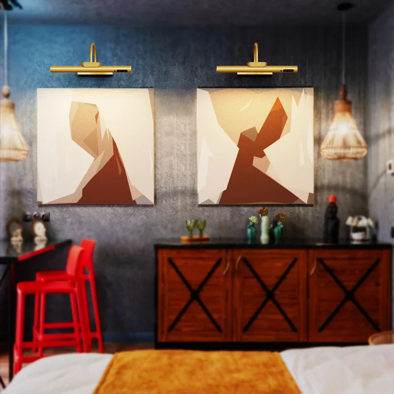 A modern interior featuring two framed abstract art pieces illuminated by wall mounted LED picture lights above wooden cabine