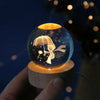 A crystal ball night light showing a silhouette of an umbrella and a figure against a dark background.