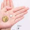 A hand holds a round gold coin magnetic sticker and a silver bar for scale.