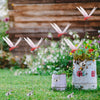 Realistic dragonfly clips are displayed on grass with various flowers and a weathered galvanized bucket.