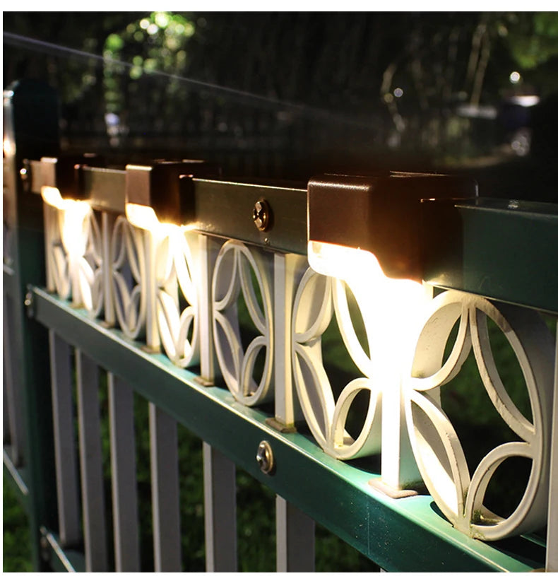 A row of solar LED outdoor deck lights with white decorative panels mounted on a green railing.