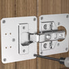 A stainless steel cabinet door hinge repair plate kit mounted on a wooden surface.