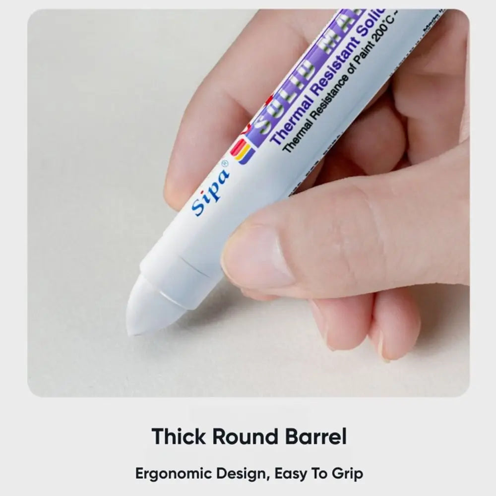 A hand holds a purple and white paint marker pen with a thick round barrel for writing.