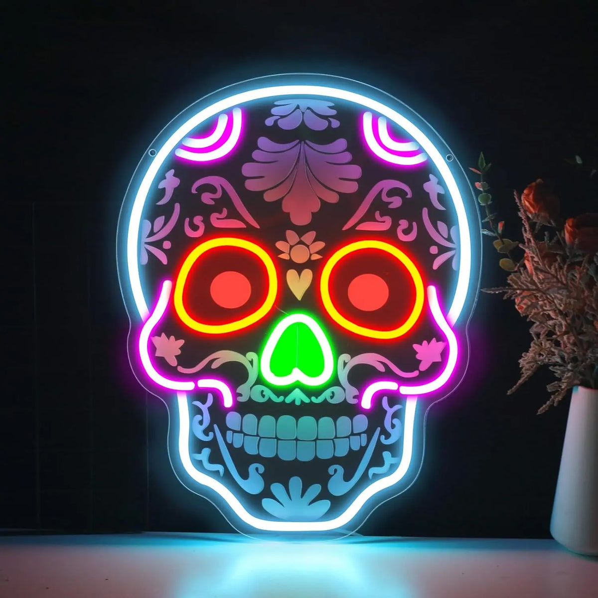 A glowing neon sign shaped like a skull with vibrant pink, orange, and green internal lights against a dark background.