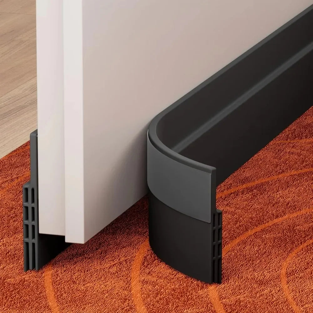 A black door draft stopper seal strip is shown installed on a white door frame resting on an orange carpet.