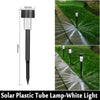 A black solar plastic tube lamp mounted on a stake, illuminating a pathway with white light.