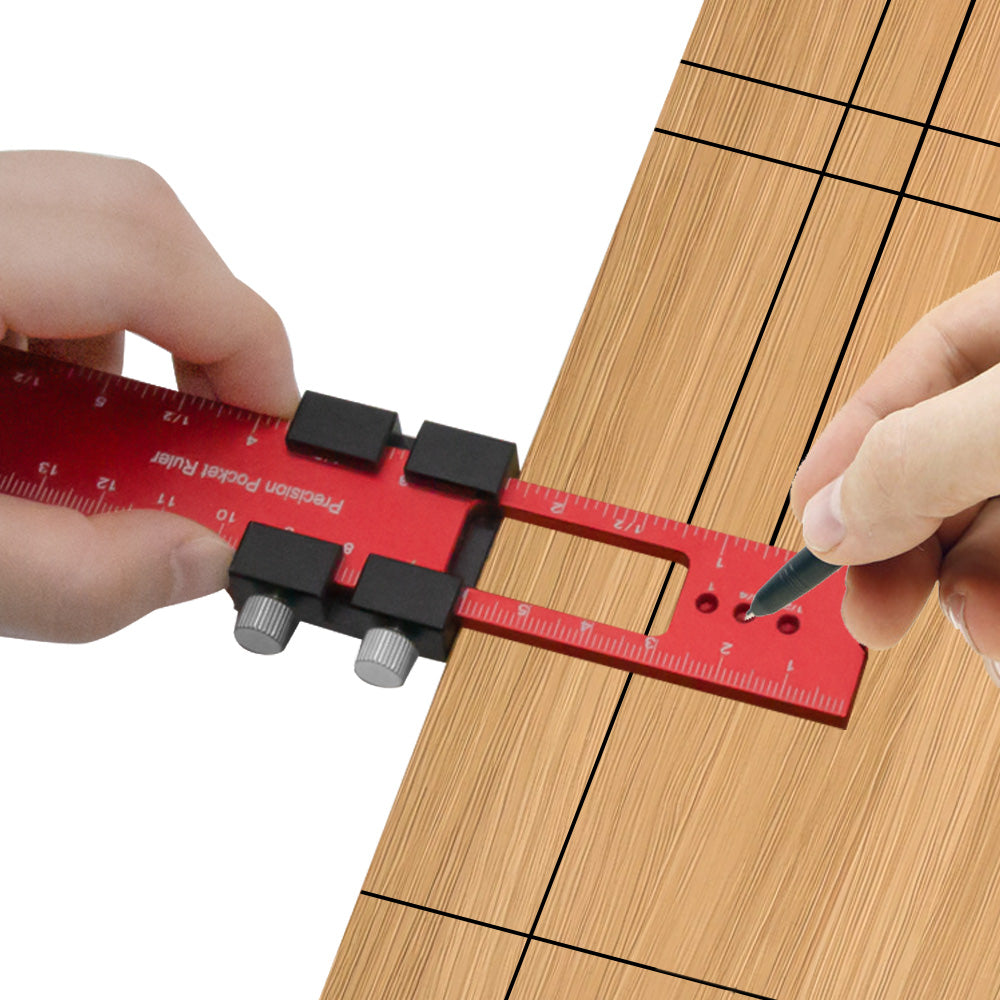 A hand uses a red precision aluminum woodworking ruler to mark a piece of wood.