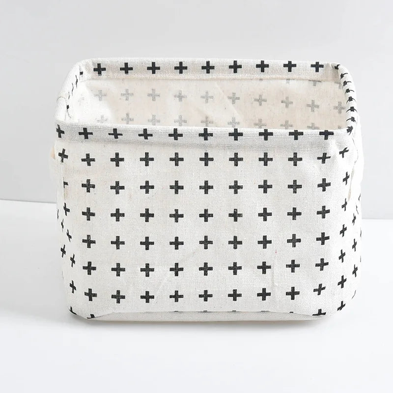 A white linen storage basket with a grid pattern of black crosses, shown from the front.
