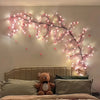 LED cherry blossom tree lights illuminating a bedroom wall above a bed.