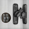 Gros plan d'une serrure à loquet de porte à clapet en alliage de zinc noir, installée sur une surface en bois clair.