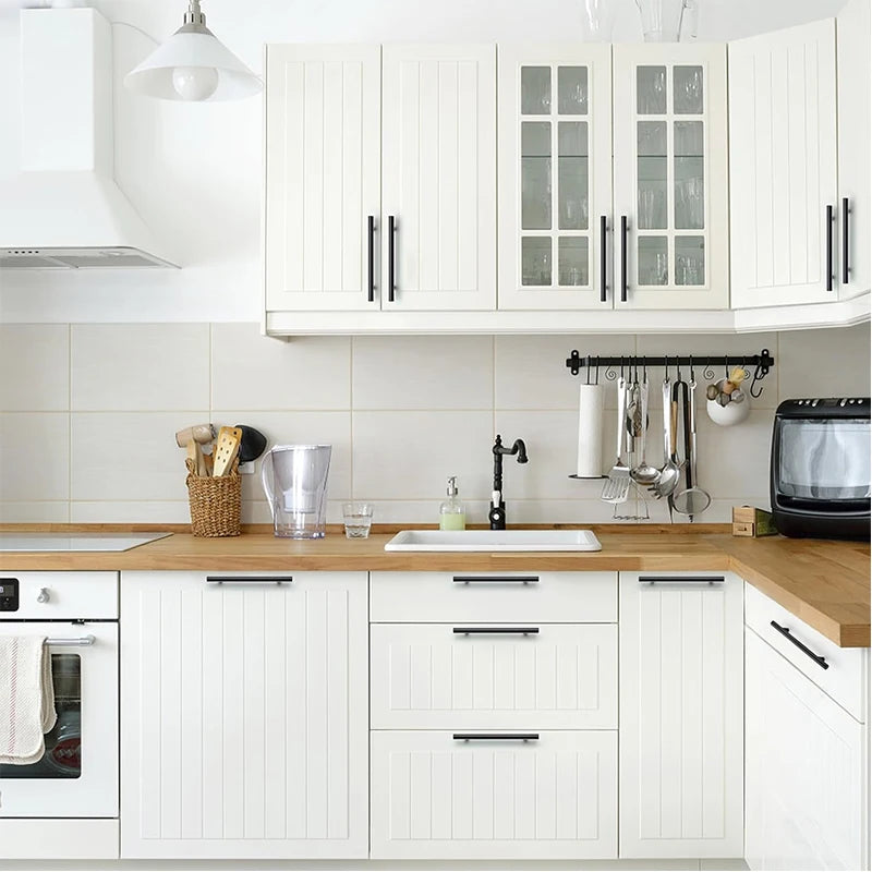 A modern kitchen featuring white cabinetry with brushed nickel and gold cabinet handles.