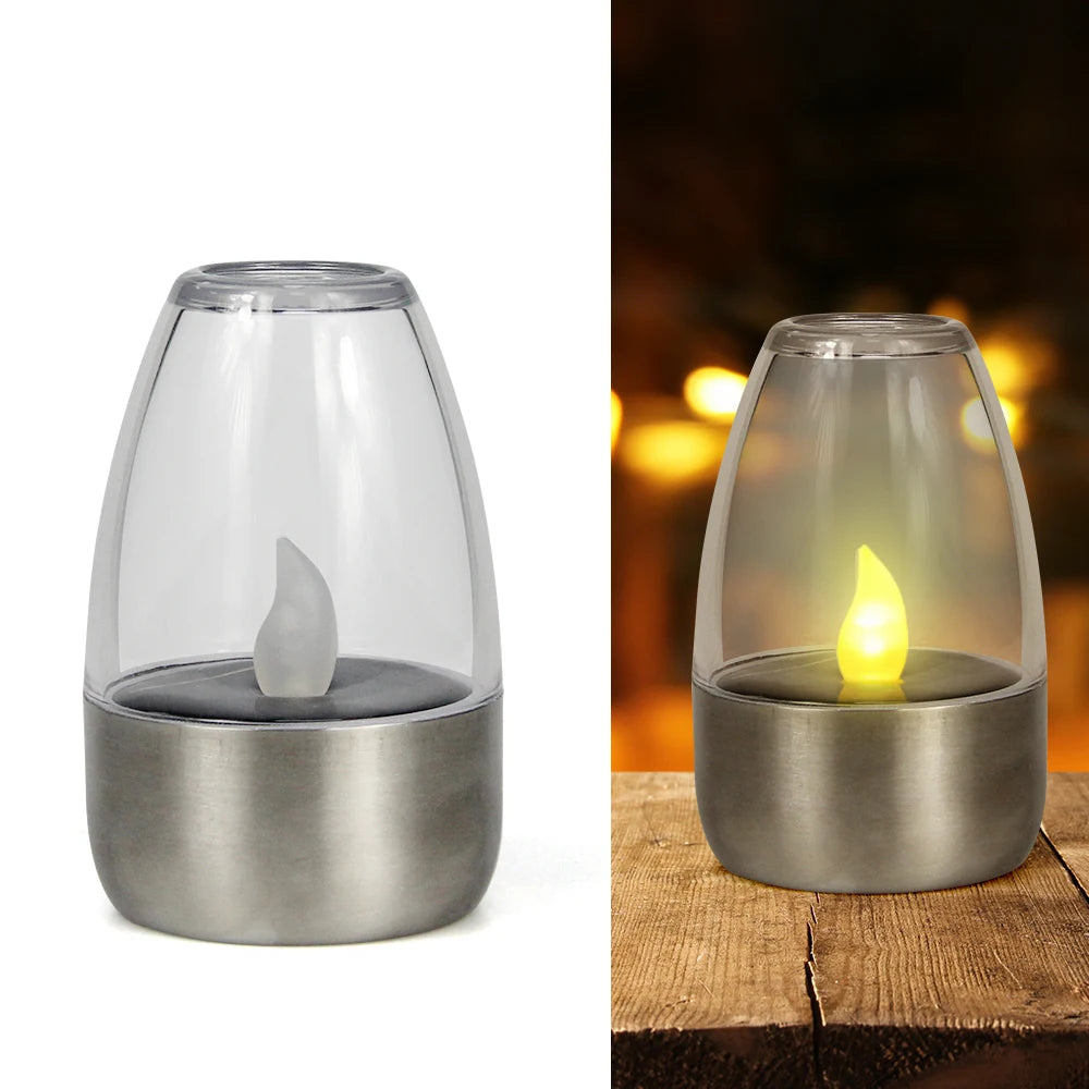 Linterna de té solar plateada sin llama con cúpula de vidrio transparente y vela encendida.