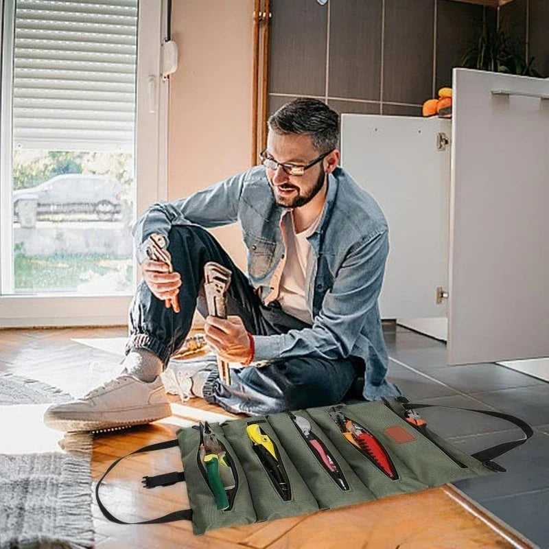 Ein Mann organisiert kleine Werkzeuge in einer grünen Tasche auf einem Holztable.