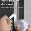 A hand is applying a white metal security door seal tape to the edge of a door frame.