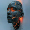 A dark resin sculpture of a human head with glowing orange cracks mounted on a wall.