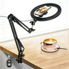 A black professional overhead lighting phone tripod is mounted on a wooden table, positioned above a cup of coffee.