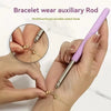 A hand is using a purple bracelet wear auxiliary rod with a metal hook to fasten a delicate gold chain bracelet.