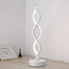 A white, wavy glass desk lamp with a modern design standing on a round base.