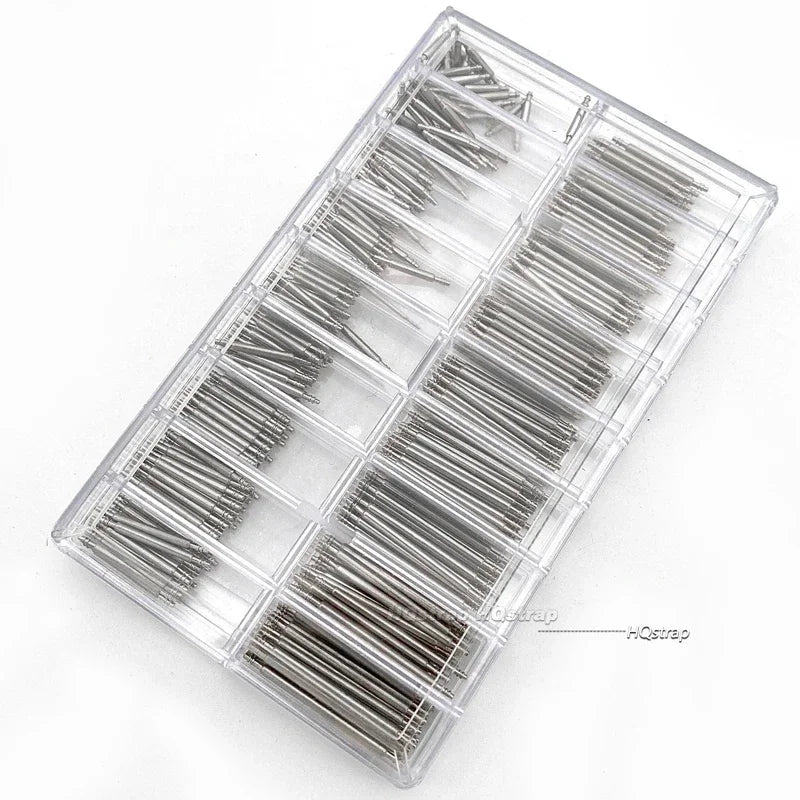 A clear plastic tray containing numerous stainless steel watch repair pins and spring bars.