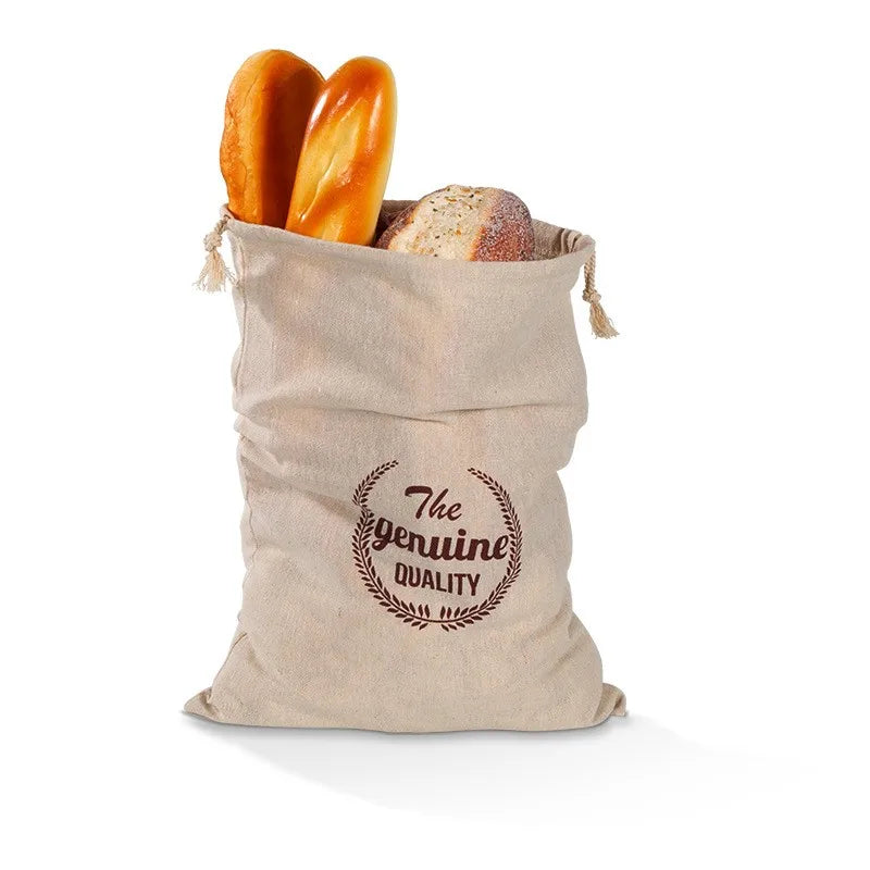 A beige linen drawstring bag filled with two bread rolls and a round loaf of bread.