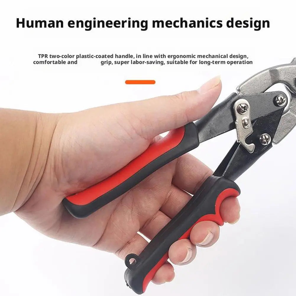 A hand holds a pair of red and black plastic-coated tin snips shears for metal cutting.