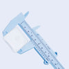 A light blue precision plastic vernier caliper set with a white measuring block and scale.