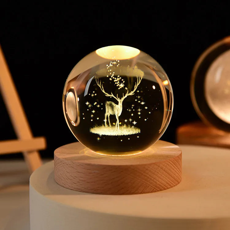 A glass crystal ball night light with a glowing interior depicting a silhouette of a deer against a dark background.