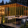 Warm yellow string lights drape across a wooden deck and pergola, illuminating greenery for outdoor decor.