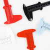 A set of precision plastic vernier calipers in red, orange, and light blue, shown next to a black measuring tool.
