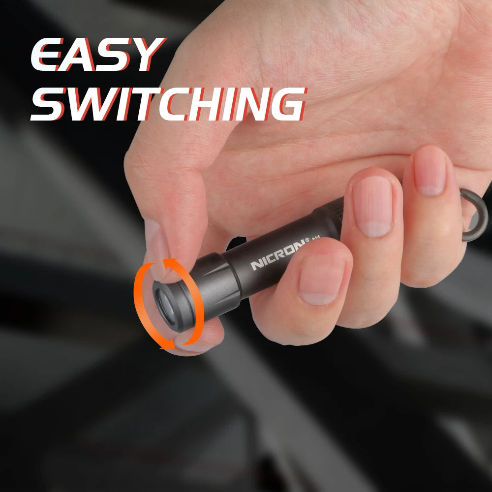A hand is shown easily switching on a black mini key chain LED flashlight.