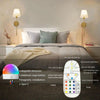 A white wireless wall lamp with a detachable bulb and various lighting modes is displayed on a bedside table.