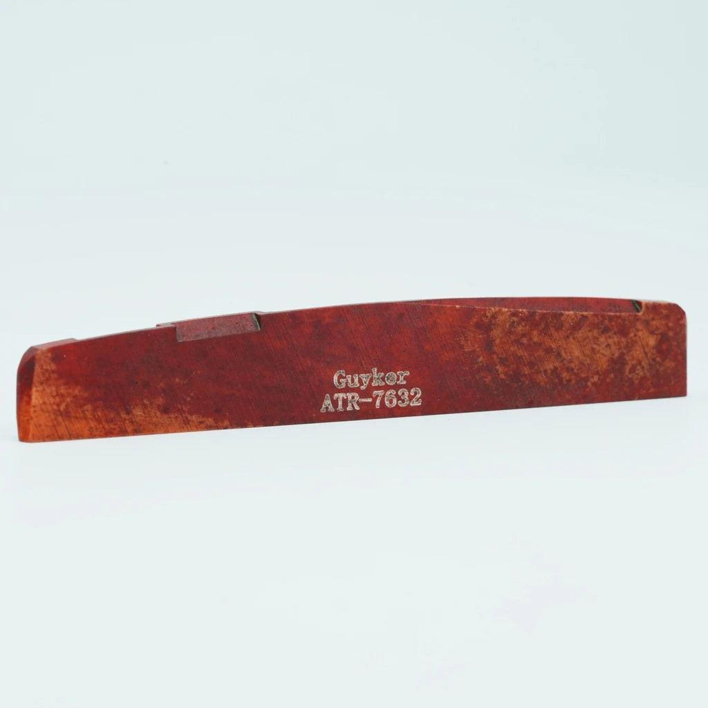 A wooden guitar bone bridge saddle with the inscription Guykor ATR-7632