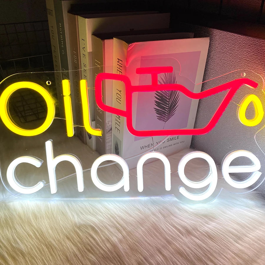 A neon sign displaying the word change with a stylized silhouette of a feather and text related to oil change.