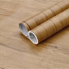 Two rolls of wood grain vinyl wall contact paper lying on a wooden surface.