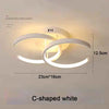Lámpara de techo LED moderna blanca en forma de C iluminando una habitación.