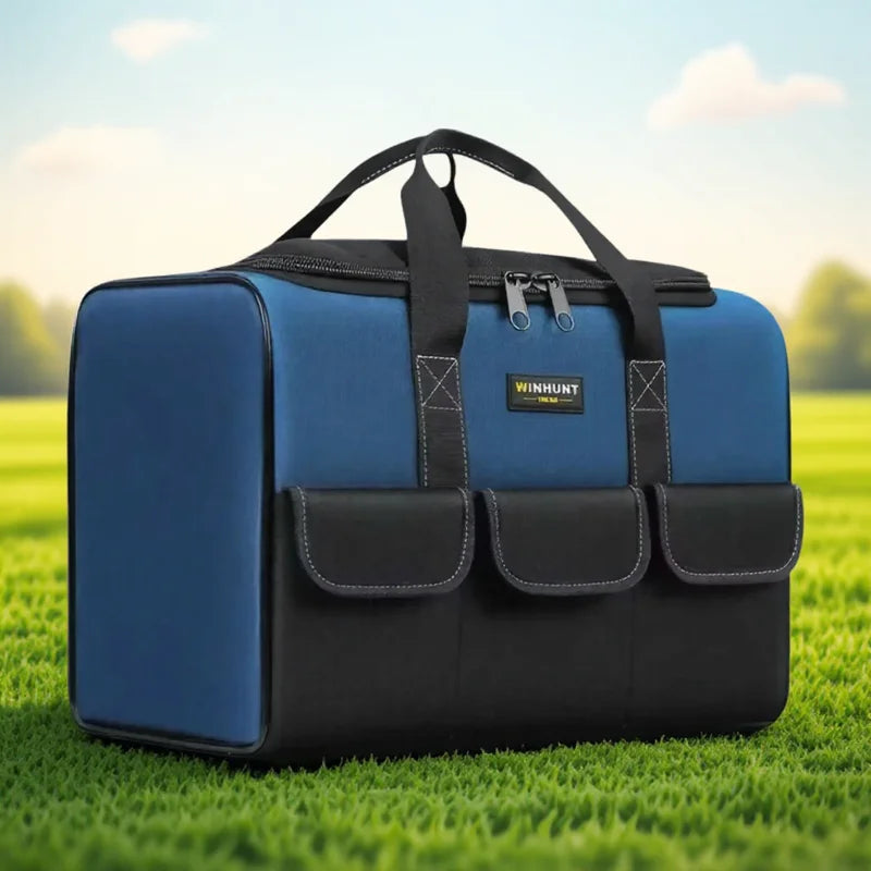 A dark blue and black heavy duty multi-compartment tool organizer bag resting on green grass.