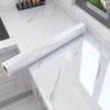 A roll of white marble self-adhesive waterproof contact paper displayed on a modern kitchen countertop.
