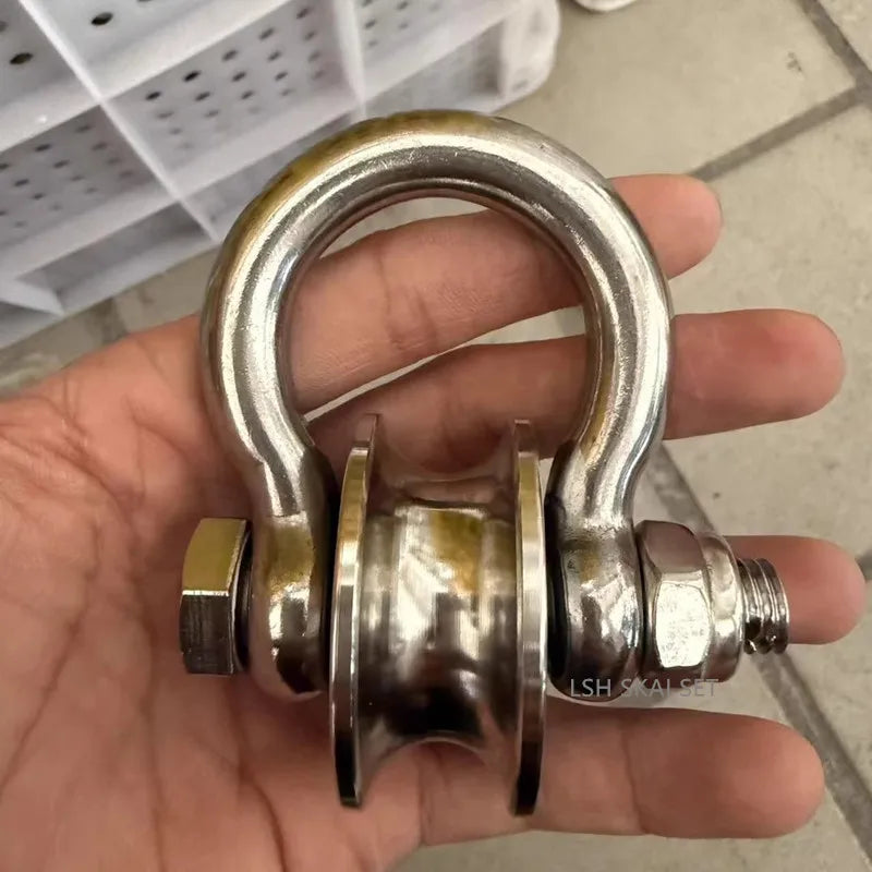 A hand holds a heavy-duty stainless steel buckle pulley with a smooth, curved handle and threaded end.