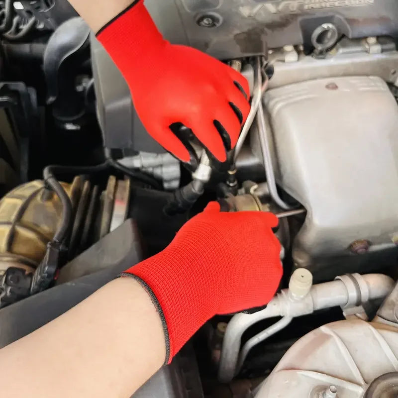 A hand wearing a bright red nitrile protective work glove is working on an engine component.