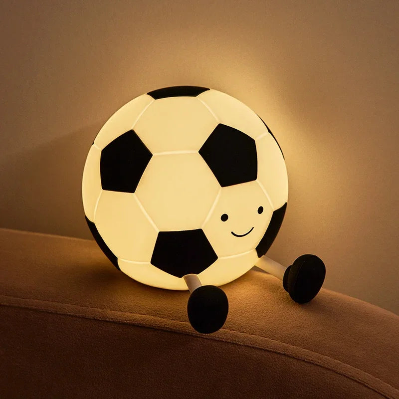 A silicone night light shaped like a soccer ball illuminates a bedside area.