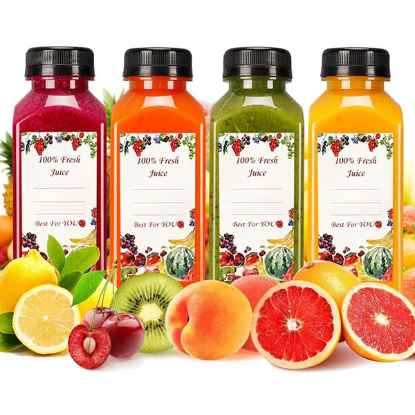 Vier Glasflaschen frischen Saft in verschiedenen Farben, darunter rot, orange, grün und gelb, neben frischem Obst