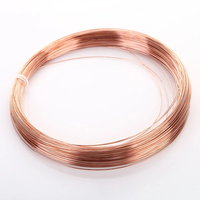 A coil of high-conductivity bare copper wire lying on a white surface.